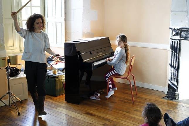 élève jouant du piano avec son professeur de musique