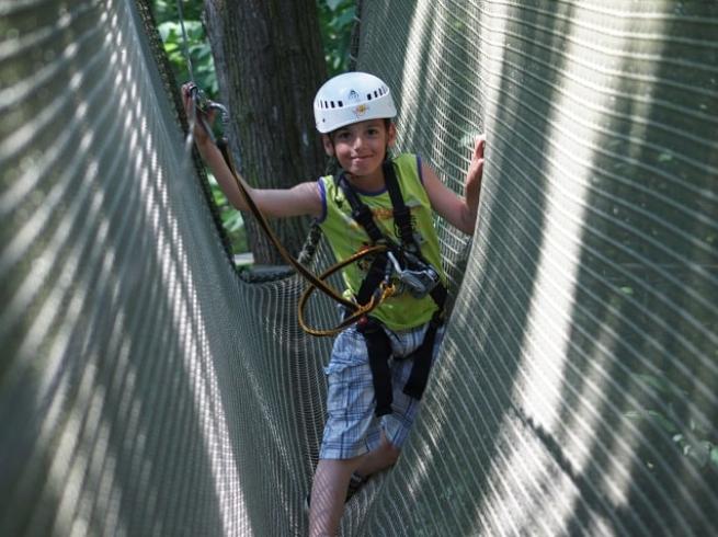 enfant qui fait de l'accrobranche heureux