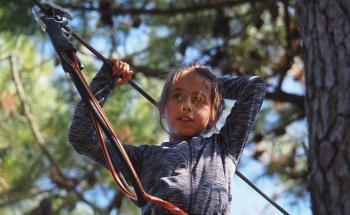 Enfant qui fait de l'accrobranche dans les arbres